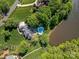 An aerial view of a home with a pool, patio, and large landscaped lot near a lake and trees at 1700 White Pond Ln, Waxhaw, NC 28173