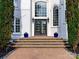 Elegant front entrance with a beautiful door, stone steps, potted plants, and stylish sconces at 1700 White Pond Ln, Waxhaw, NC 28173