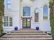 Inviting front entrance with a beautiful door, stone steps, potted plants, and stylish sconces at 1700 White Pond Ln, Waxhaw, NC 28173