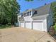 Exterior view of the attached three-car garage featuring white doors and stucco siding at 1700 White Pond Ln, Waxhaw, NC 28173