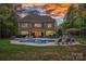 A backyard featuring a pool and a patio with lounge chairs, perfect for outdoor relaxation and entertaining under a vibrant sunset at 1717 Brawley School Rd, Mooresville, NC 28117