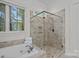 Bathroom featuring a soaking tub and frameless glass shower with beige tiling at 1717 Brawley School Rd, Mooresville, NC 28117