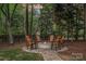 Cozy fire pit with stone surround and seating, set in a private, wooded backyard, perfect for outdoor gatherings at 1717 Brawley School Rd, Mooresville, NC 28117