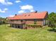 Brick home with red metal roof and a large wooden deck overlooking the landscaped yard and a walkout basement at 2251 Old Applewood Ln # 9, Iron Station, NC 28080