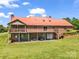 Spacious brick home featuring a red metal roof, large deck, walkout basement, and well-maintained lawn at 2251 Old Applewood Ln # 9, Iron Station, NC 28080