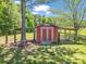 Charming red storage shed with blue doors and matching porticos stands under a large shade tree at 2251 Old Applewood Ln # 9, Iron Station, NC 28080