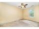 This bedroom has yellow walls, a ceiling fan, a window and a carpet that needs replacing at 248 Pangle Dr, Charlotte, NC 28217