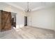 Spacious bedroom with a modern chandelier and a rustic barn door leading to the bathroom at 2586 Lee Lawing Rd, Lincolnton, NC 28092