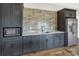 Modern bar area featuring gray cabinets, a microwave, a stainless steel refrigerator, and a tiled backsplash at 264 Fairway Shores Rd, Mount Gilead, NC 27306