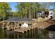 Beautiful exterior view of a modern home with a boathouse on the lake surrounded by lush trees at 264 Fairway Shores Rd, Mount Gilead, NC 27306
