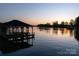 Stunning sunset lake view featuring a boathouse with a covered area for relaxation at 264 Fairway Shores Rd, Mount Gilead, NC 27306