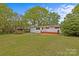 View of the back of the house, green lawn and trees from the painted wood deck at 3108 Anne St, Charlotte, NC 28205
