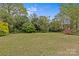 Expansive green lawn backyard with mature trees, viewed from the painted wood deck at 3108 Anne St, Charlotte, NC 28205