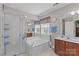 Bright bathroom features a glass-enclosed shower, soaking tub, and double sink vanity with wood cabinets at 3831 Robeson Creek Dr, Charlotte, NC 28270