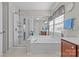 Bright bathroom features a glass-enclosed shower, soaking tub, and vanity. Natural light from the window at 3831 Robeson Creek Dr, Charlotte, NC 28270