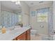 Well-lit bathroom featuring a single sink vanity with wood cabinets and a shower with blue patterned curtains at 3831 Robeson Creek Dr, Charlotte, NC 28270