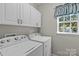 Functional laundry room with washer, dryer, storage cabinets, and natural light for efficient chores at 3831 Robeson Creek Dr, Charlotte, NC 28270