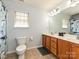 Well-lit bathroom with double vanity, wooden cabinets, and patterned shower curtain at 3914 Cassidy Dr, Waxhaw, NC 28173
