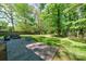 A spacious backyard has a beautiful stone patio with ample seating and plenty of green space surrounded by mature trees at 4313 Sudbury Rd, Charlotte, NC 28205