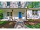 Inviting front porch showcasing a blue front door, white brick, wooden columns, and landscaped flower beds at 4313 Sudbury Rd, Charlotte, NC 28205