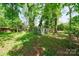 The backyard features a storage shed with windows and white trim, nestled among mature trees and greenery at 4313 Sudbury Rd, Charlotte, NC 28205