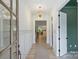 Inviting hallway with hardwood floors, white wainscoting, a statement light fixture, and a partial view of the kitchen at 5010 Ohm Ln, Charlotte, NC 28270
