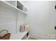 Hall tree with white shiplap, open shelving, and bench with pillows near a doorway at 5010 Ohm Ln, Charlotte, NC 28270