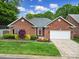 Charming brick home with a well-manicured lawn, flowerbeds, and attached two-car garage at 5404 Dunedin Ln, Charlotte, NC 28270