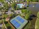 Aerial view of tennis courts, community pool, parking, and houses by the pond surrounded by lush trees at 551 Hemmings Nw Pl, Concord, NC 28027