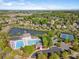 An aerial view showcases a community pool, lake, and neighborhood with lush trees under a bright blue sky at 551 Hemmings Nw Pl, Concord, NC 28027