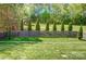 Backyard with a wooden fence, trimmed evergreens and lush grass at 5628 Selkirkshire Rd, Charlotte, NC 28278