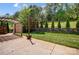 Inviting backyard featuring a covered patio, string lights, and a well-manicured lawn with mature trees and fence at 5628 Selkirkshire Rd, Charlotte, NC 28278