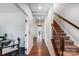 Long hallway with hardwood floors leading to other rooms, staircase with decorative iron railing and light gray walls at 5628 Selkirkshire Rd, Charlotte, NC 28278