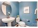 Stylish powder room featuring blue walls, a pedestal sink, and modern fixtures and decor at 5628 Selkirkshire Rd, Charlotte, NC 28278