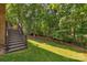 Spacious backyard with a wooden staircase leading to a lush, green lawn and wooded area at 6017 Summerston Pl, Charlotte, NC 28277