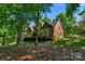 Rear view of a brick home featuring a large deck, a lush lawn, and mature trees at 6017 Summerston Pl, Charlotte, NC 28277
