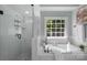 This is a well-lit bathroom showcasing a shower, bathtub, and garden window, offering a spa-like experience at 6017 Summerston Pl, Charlotte, NC 28277