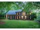 Charming brick home with well-lit windows, a green lawn, and mature trees showcasing a serene residential atmosphere at 6017 Summerston Pl, Charlotte, NC 28277