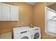 Bright laundry room with a Whirlpool washer and dryer and white cabinets at 6017 Summerston Pl, Charlotte, NC 28277