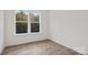 Bright, minimalist bedroom featuring wood-look floors, white walls, and a window with a view of the trees at 655 District Ct, Fort Mill, SC 29708