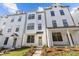 Eye-level exterior shows the front of a three-story modern white townhome with black window trim and a covered porch at 655 District Ct, Fort Mill, SC 29708