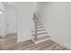Hallway features wood-look floors, white walls, and a staircase leading to the upper level, with a glimpse of the front door at 655 District Ct, Fort Mill, SC 29708
