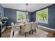 Dining room featuring blue walls, wood floors, a modern light fixture, and large windows overlooking the yard at 700 Oakland Ave, Charlotte, NC 28204
