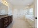 Bathroom with dual sinks, dark cabinets, a separate shower and tub, and neutral tile floors at 79411 Ridgehaven Rd, Indian Land, SC 29720