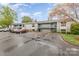 A two-story condo building features muted grey siding with a parking lot and car on a cloudy day at 10967 Harrowfield Rd, Charlotte, NC 28226