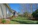 Landscaped backyard featuring a well-maintained lawn, flower beds, mature trees, and a view of the home's exterior at 115 Keswick Ln, Mooresville, NC 28117