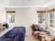 Sunlit bedroom featuring a chaise lounge, comfortable bedding, and tranquil views from the dual windows at 115 Keswick Ln, Mooresville, NC 28117
