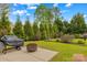 Landscaped backyard with green lawn, fire pit on patio, and privacy provided by mature trees at 12746 Bravington Rd, Huntersville, NC 28078