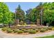 Landscaped community entrance with stone features, colorful flowerbeds, and American and North Carolina flags at 12746 Bravington Rd, Huntersville, NC 28078