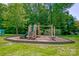 Community playground with slide, climbing bars, and cushioned ground surrounded by mature trees at 12746 Bravington Rd, Huntersville, NC 28078